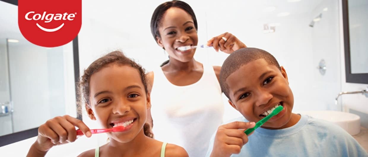 Black family of mother and children  brushes teeth together and practices proper oral care.