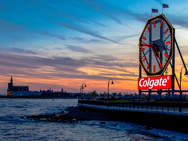 sea ​​shore, colgate logo in the background under a large clock with red hands