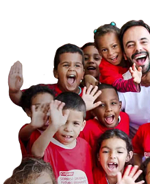 A group of smiling children waving, wearing red Colgate t-shirts, alongside a smiling man in a white shirt.