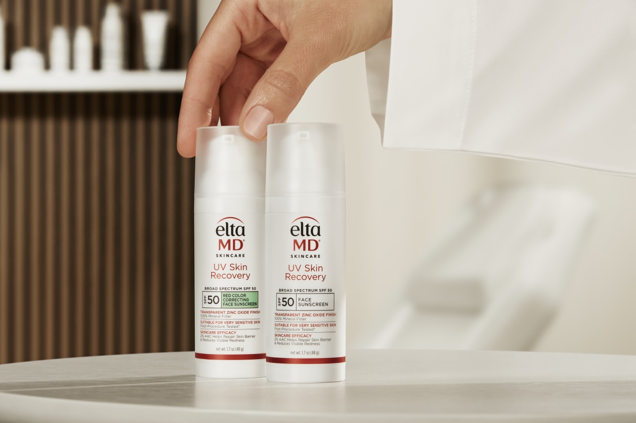 EltaMD sunscreen products placed on white table by a dermatologist's hand.