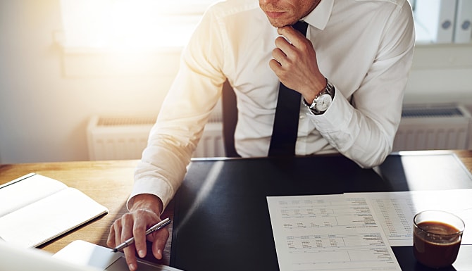 Man working on a laptop with papers around him