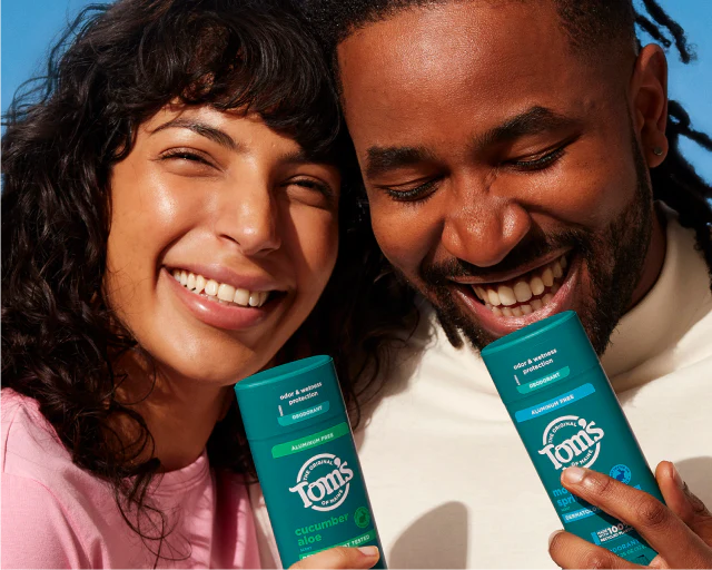 Happy couple holding Tom's of Maine deodorant products and smiling.