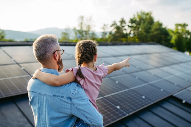 Father and daughter on a roof with solar panels