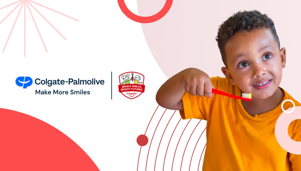 A smiling child in an orange t-shirt holds a red Colgate toothbrush to his teeth. On the left is the blue Colgate-Palmolive corporate logo with the text "Make More Smiles," alongside the "Bright Smiles, Bright Futures Colgate" red badge. The light pink background features red and white geometric lines.
