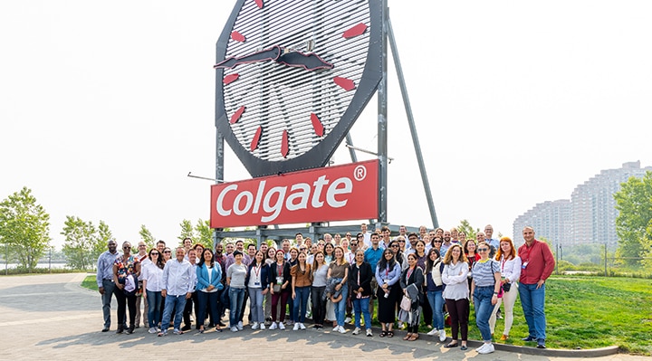  Large group of Colgate-Palmolive employees posing in front of the Colgate Clock during a team event.