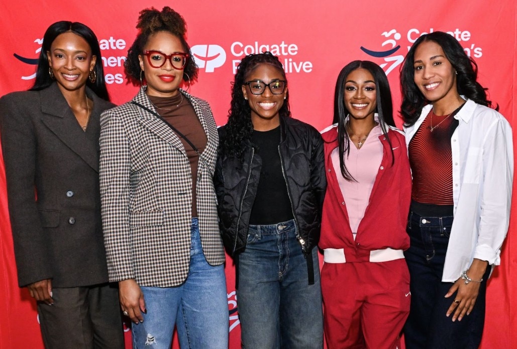 girls smiling on a  stage with colgate palmolive background in red