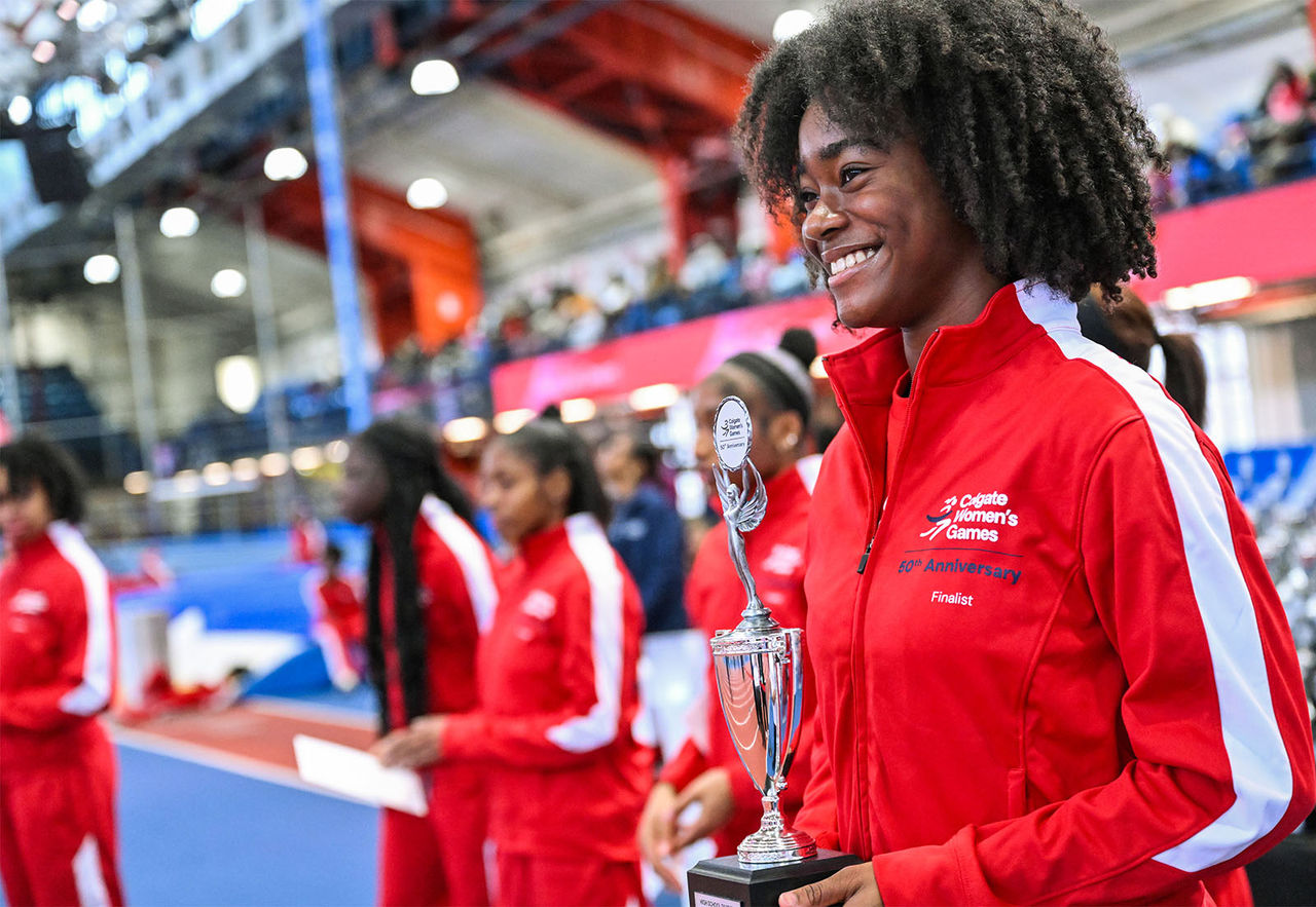A smiling finalist holds her trophy at the 50th Anniversary Colgate Women's Games indoor track event.