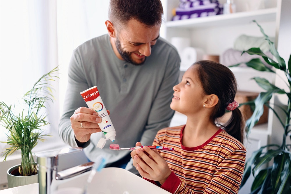 father and daughter smiling with colgate toothpaste on hands
