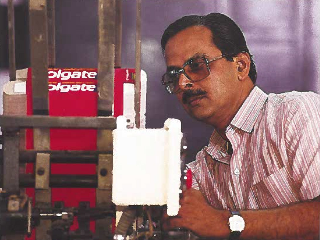 Historic photo of man by equipment producing Colgate boxes.