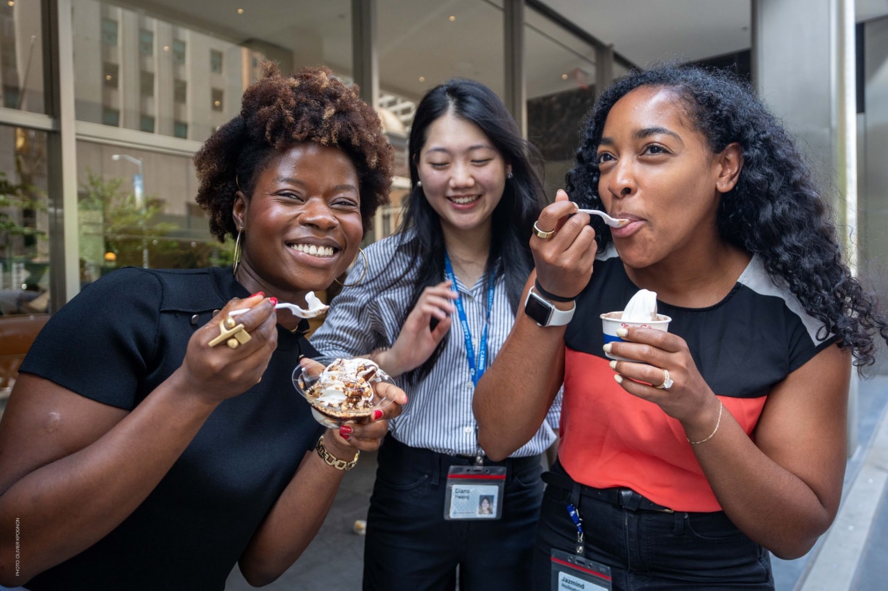 Three Colgate-Palmolive employees enjoying ice cream desserts together during a company event.